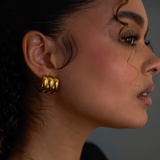 Close-up of a woman wearing gold hoop earrings with a blurred background