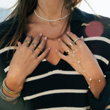 Person wearing a black and white striped sweater with jewelry and nail polish.