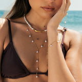Woman in a black bikini with pearl lariat necklace and pearl jewelry on a beach