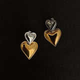 Heart-shaped earrings in gold and silver on a black background