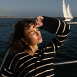 Woman in a blue and white striped sweater on a boat with waterproof jewelry and pearl choker