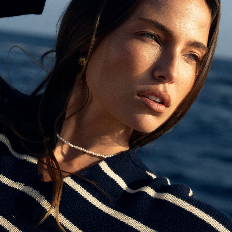 Woman with striped sweater and petite pearl necklace