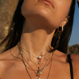 Close-up of a person wearing multiple gold necklaces with various pendants